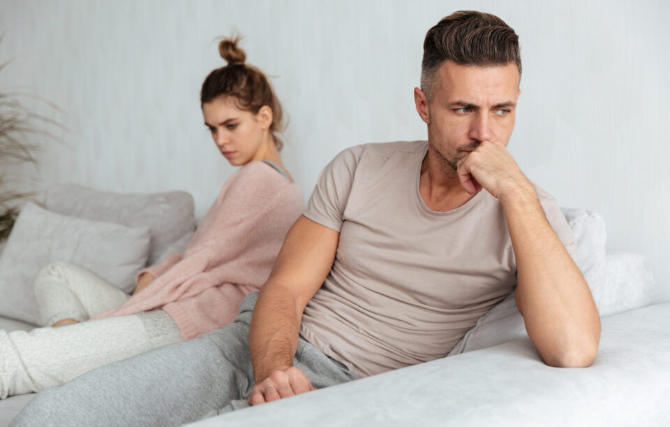 Image of Quarrelled lovely couple sitting separately on couch at home